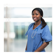 A Black British nurse with a pony tail on a blue uniform. She is smiling while looking at the camera.