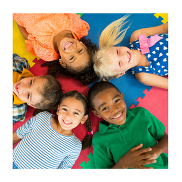 Five smiling children lying in a circle on colourful mats.