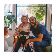 A child and father smiling at the camera. The child has his hips and legs attached to a walking support equipment.