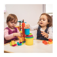 Two small children playing together. They are stacking blocks one on top of the other.