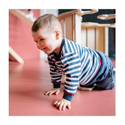 A toddle with a striped blue and white top crawling on a pink floor.