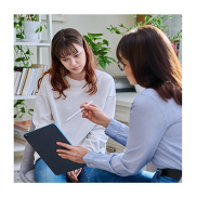 Two women talking to each other while looking at a tablet.