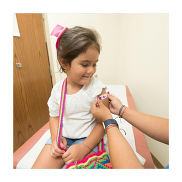 Child sitting on a chair having a plaster put on her arm.