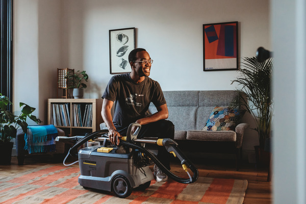 A man is sitting in a freshly cleaned flat with a Karcher carpet cleaner.