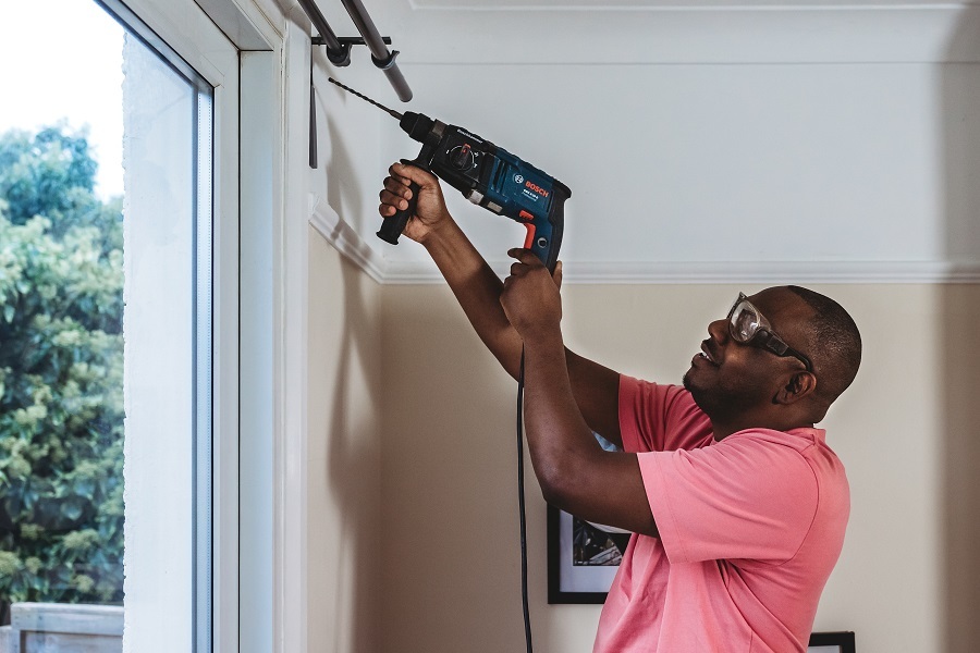 Man putting up a curtain pole using an electric drill borrowed from the Library of things