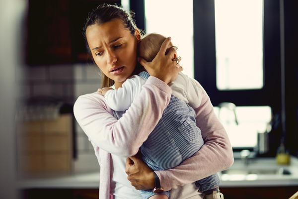 Mother holding a new baby and looking anxious and stressed