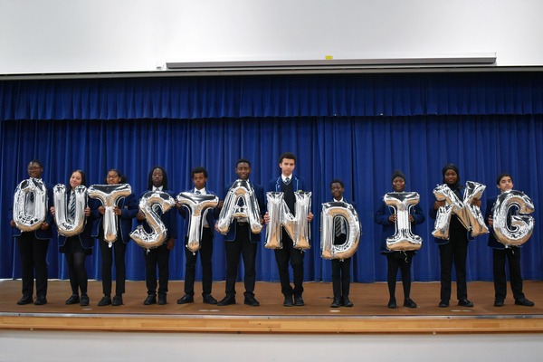 Harris Academy Peckham pupils hold up silver balloons spelling outstanding.