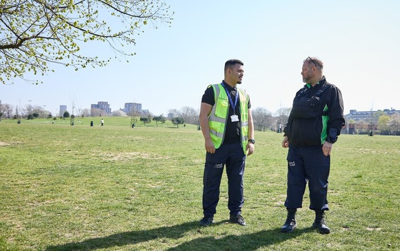Two uniformed littering officers stand in a park