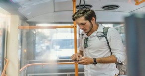 Young man standing on a bus.