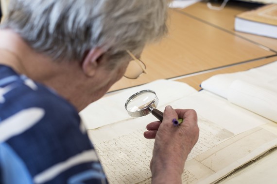 Volunteer working on a document and holding a magnifying glass