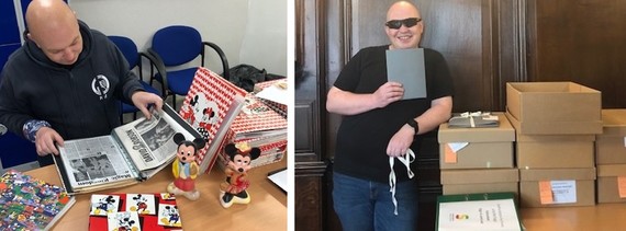 Volunteer Kevin Mottram seated - working through Micky Mouse memorabilia - and standing with completed accession boxes