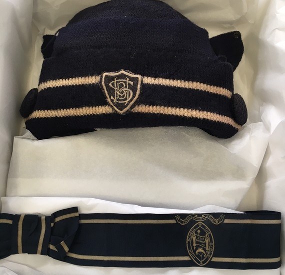Knitted navy blue hat with gold stripes at band and school badge for Burton Girls' High School with blue ribbon below