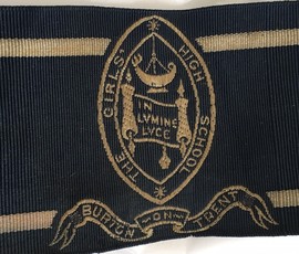 Detail of school badge on ribbon. Oval shape with Burton Girls' High School stitched at edge. 