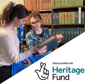 Colour photograph of two volunteers with leather bound book and NLHF logo