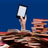 Hand holding smartphone poking out of a pile of books