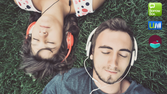 Man and woman lying on the grass wearing headphones