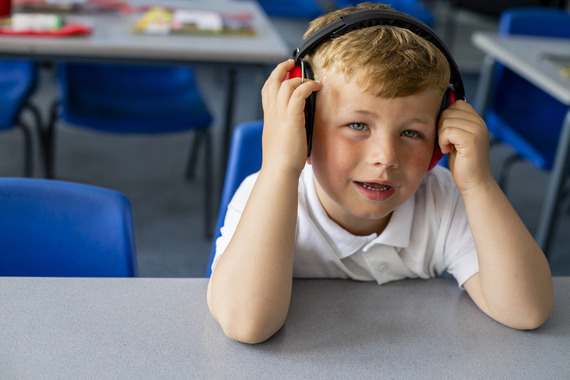 young child in classroom wearing ear defenders