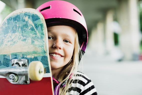 girl wearing helmet and holding skateboard