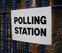 White Polling station sign attached to railings