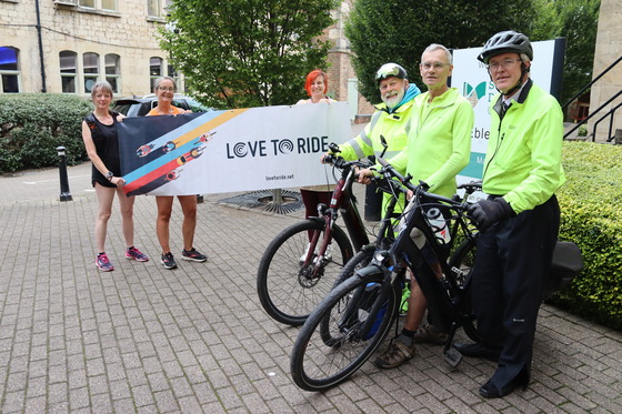 Stroud District Council staff and members pose with bicycles and a Love To Ride banner, outside Ebley Mill, SDC's headquarters