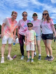 A group of people wearing white t shirts covered in coloured powder paint