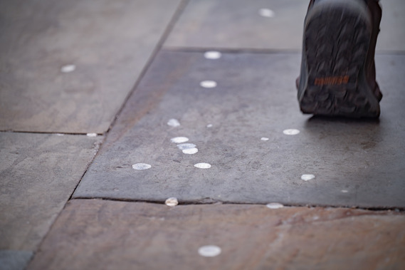 A person's foot walking on a pavement with blobs of chewing gum stuck to it