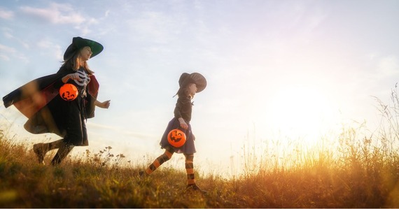 Two children in halloween costume running in the countryside