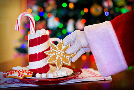 Santa's hand reaching for a cookie and hot chocolate