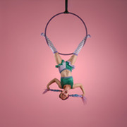 Elf character dangling from aerial hoop dressed in purple and green outfit with purple braided hair