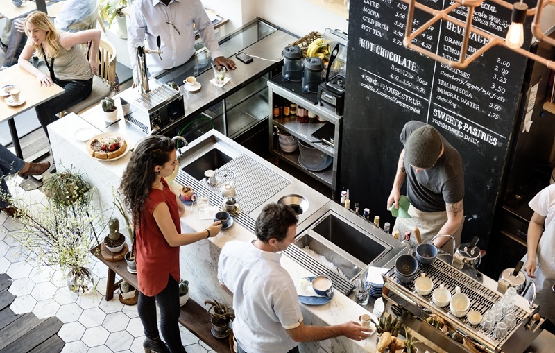 A scene in a cafe with drinks being served at a bar.