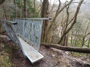 Galvanised bridge with narrow single foot step over walkway  - similar to a rope bridge in a 'v' style with wider handrails
