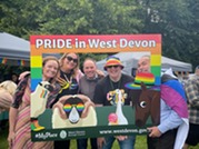 Small group of people gather inside of a Pride themed photo frame