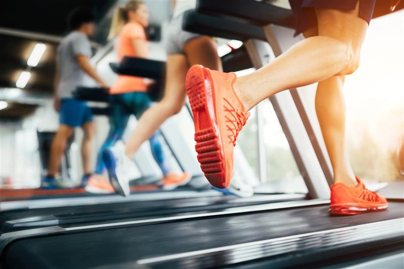 People running on treadmills in a gym, focused on feet