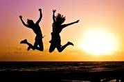 two young people jumping against a sunset background