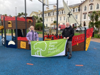 Green Spaces Projects Officer Chrissie Drew and Executive Member for Sport Recreation and Culture Cllr John Nutley holding a green flag