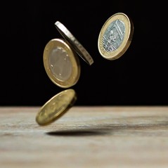 Coins falling against a dark background above a lighter surface