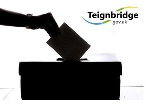 Silhouette of person putting their voting slip into the ballot box