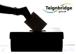 Silhouette of a hand putting a voting slip into a ballot box