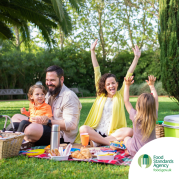 Two adults, two children enjoying a picnic.  Food Standards Agency logo