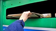 Person putting cardboard into a recycling bank