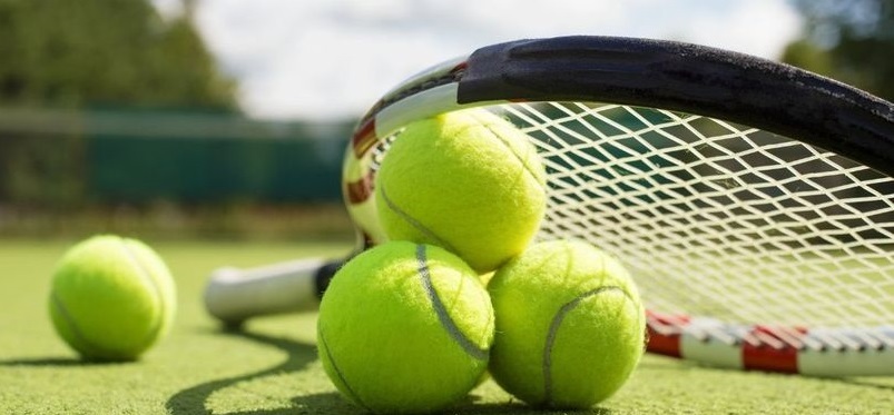 A tennis racket and four tennis balls