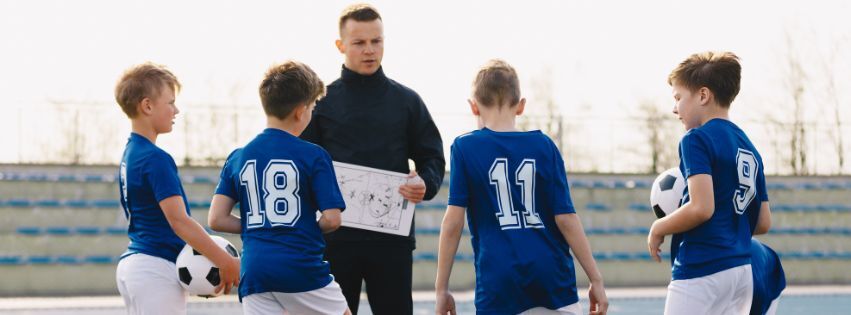 A sports coach with a four boys in football kits
