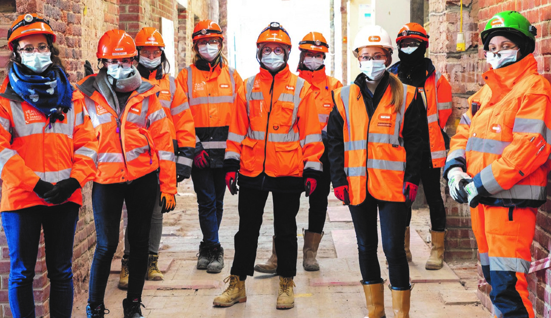 Women in hard hats and masks working in construction 
