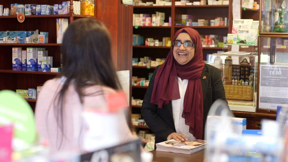 pharmacist smiling as she greets a customer
