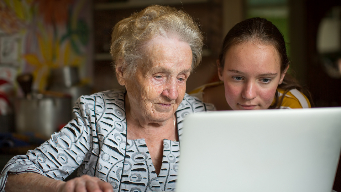 Young person showing an older person something on a laptop