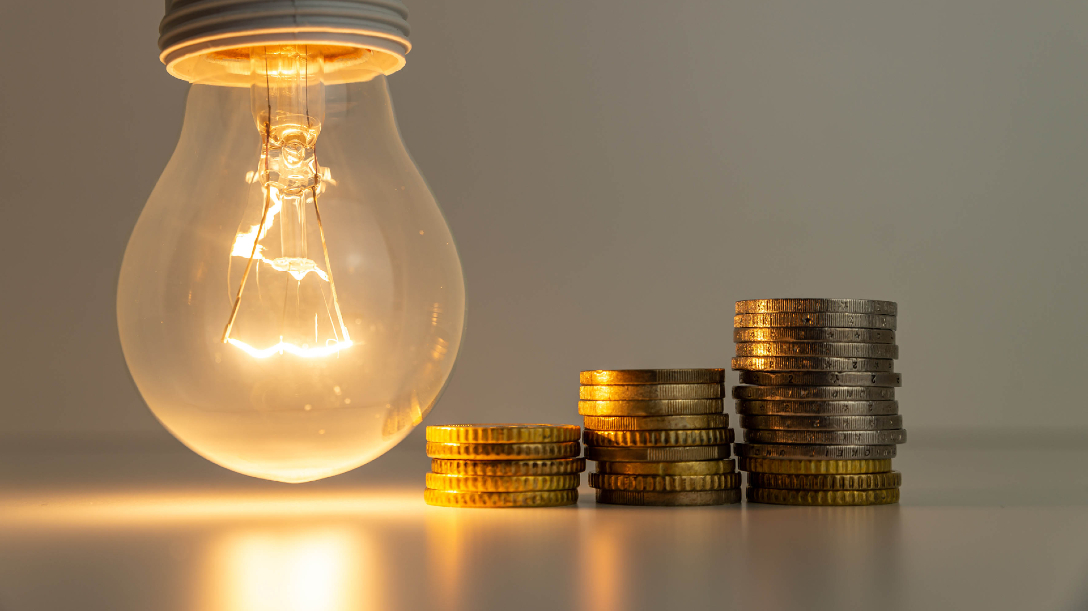 Lit lightbulb and coins