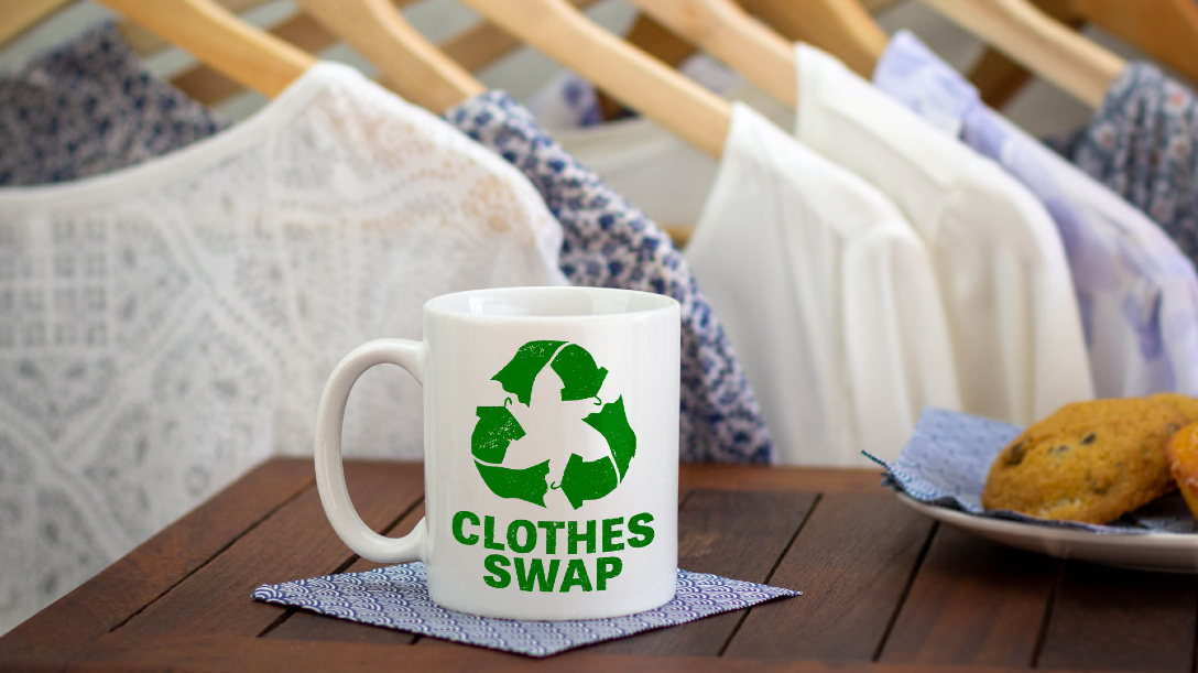 Tea mug that reads 'clothing swap' and with clothing rack behind