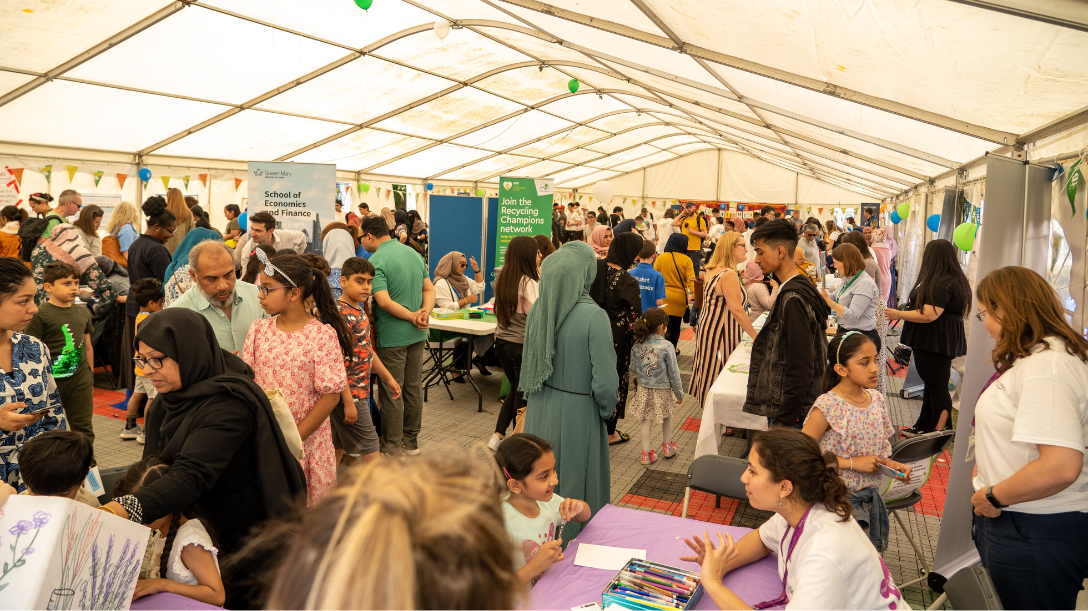 People standing around stalls and talking to people at the Festival or Communities