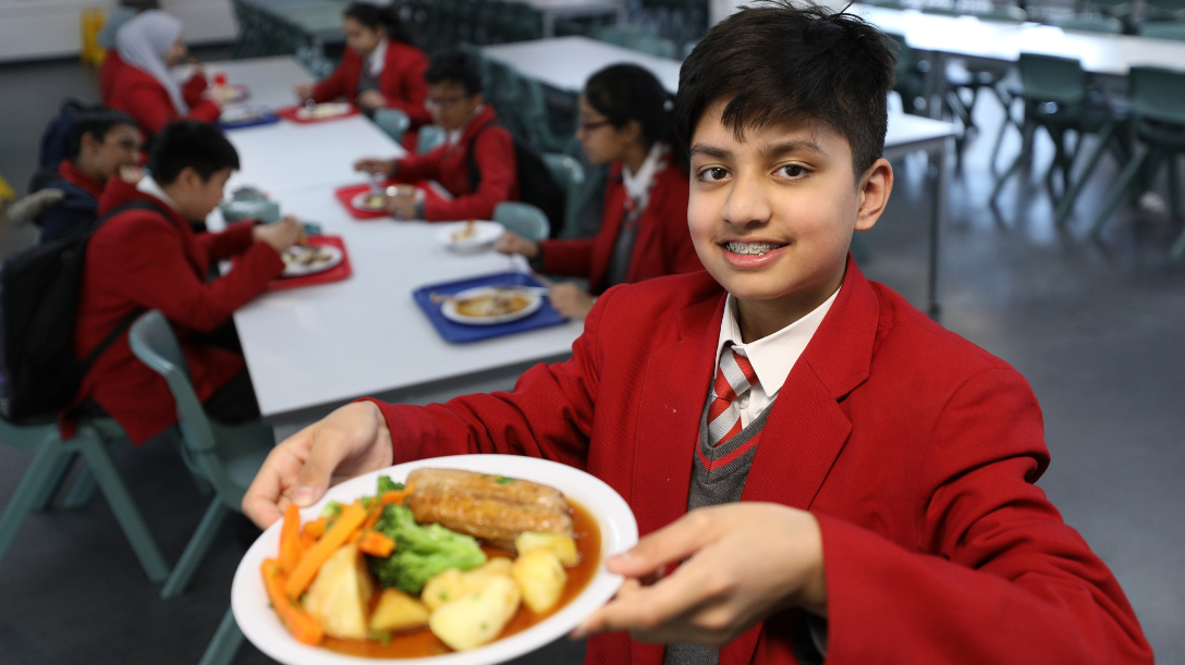 Pupil holding up their free school meal to a camera