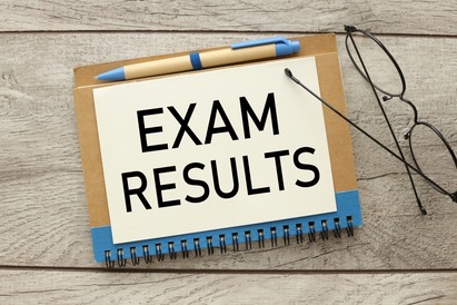 Office wooden table with paper, glasses written Exam Results with pen